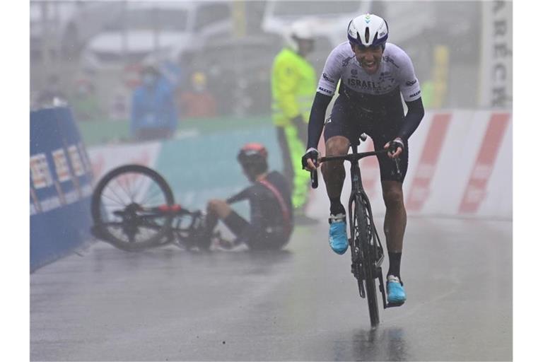 Michael Woods überquert als Etappensieger die Ziellinie. Im Hintergrund liegt der gestürzte Geraint Thomas am Boden. Foto: Jean-Christophe Bott/KEYSTONE/dpa