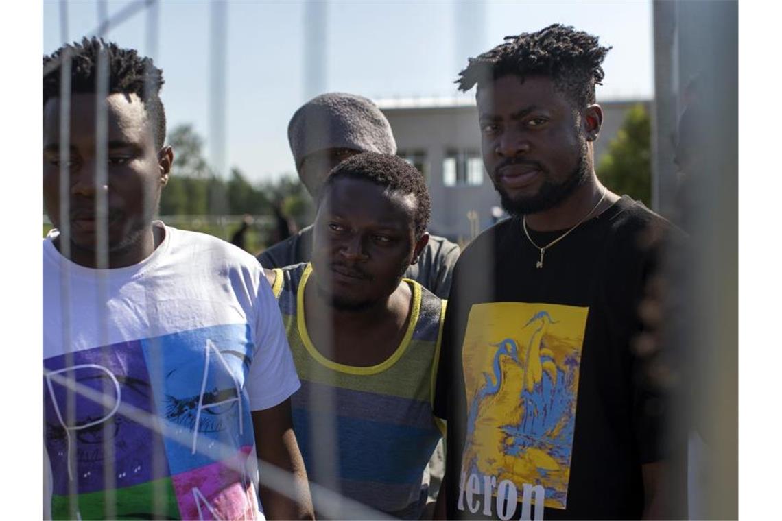 Migranten aus Kamerun stehen am Zaun eines Flüchtlingslagers in Litauen. Foto: Mindaugas Kulbis/AP/dpa