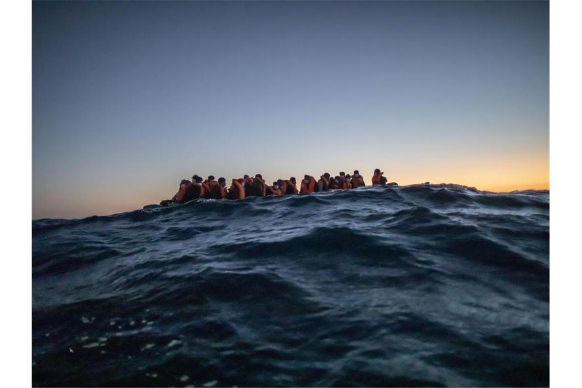 Migranten aus verschiedenen afrikanischen Nationen warten in einem Boot vor der libyschen Küste im Mittelmeer auf Helfer. Foto: Bruno Thevenin/AP/dpa