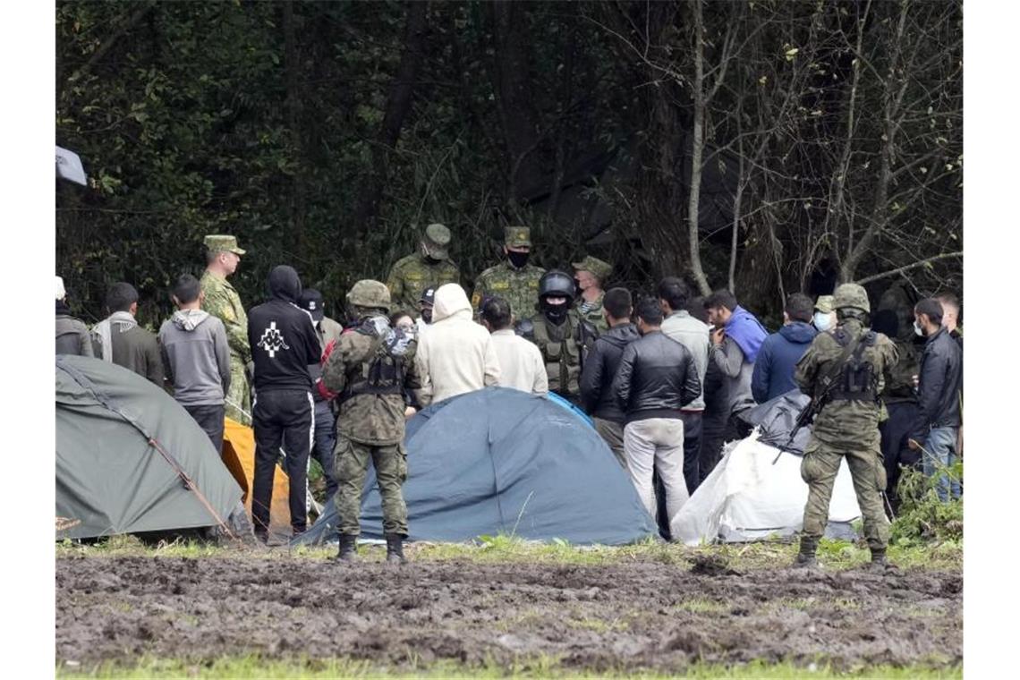 Polen verhängt Ausnahmezustand an Grenze zu Belarus Migranten, die an der Grenze zu Belarus festsitzen, werden von polnischen Beamten umstellt. Foto: Czarek Sokolowski/AP/dpa