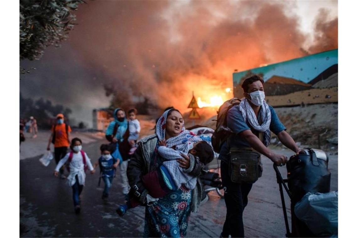 Migranten fliehen im September 2020 aus dem brennenden Flüchtlingslager Moria auf Lesbos. Foto: Petros Giannakouris/AP/dpa