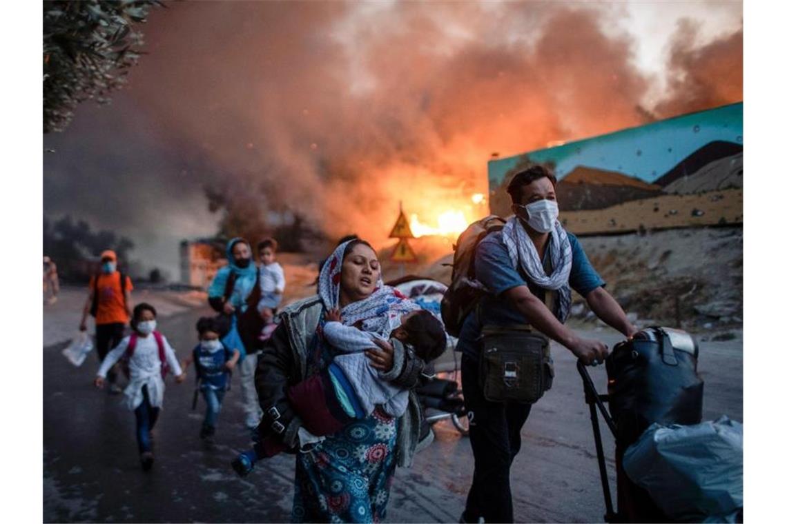 Migranten fliehen vor einem großen Feuer mit ihren Habseligkeiten aus dem Flüchtlingslager Moria. Foto: Petros Giannakouris/AP/dpa