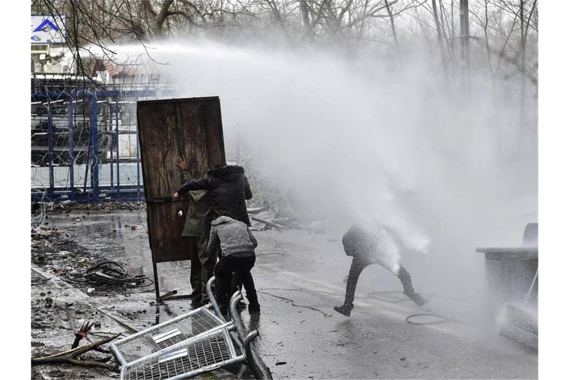 Migranten gehen an der griechisch-türkischen Grenze bei Zusammenstößen mit der griechischen Polizei in Deckung (Archiv). Foto: Ismail Coskun/IHA/dpa