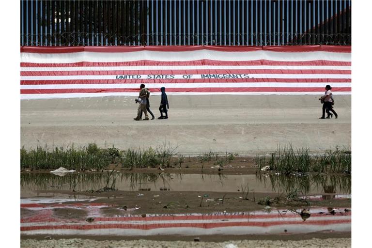Migranten gehen in Ciudad Juarez in Mexiko an einem Grenzzaun vorüber. Foto: Christian Torres/AP