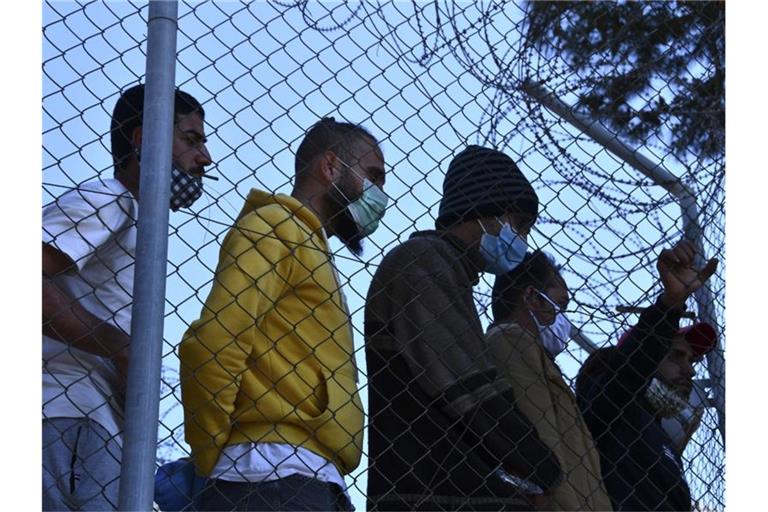 Migranten in einem Flüchtlingscamp am Hafen von Vathy auf der Insel Samos beobachten den Besuch der EU-Innenkommissarin Johansson. Foto: Michael Svarnias/AP/dpa