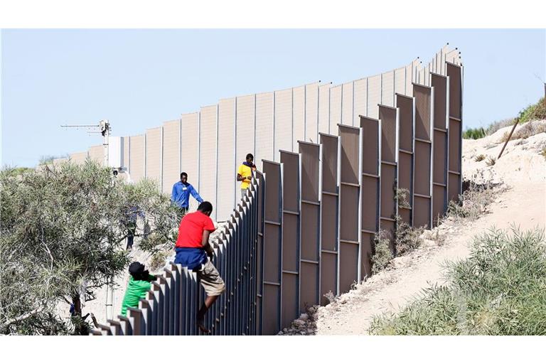 Migranten klettern über einen Zaun auf der italienischen Insel Lampedusa.