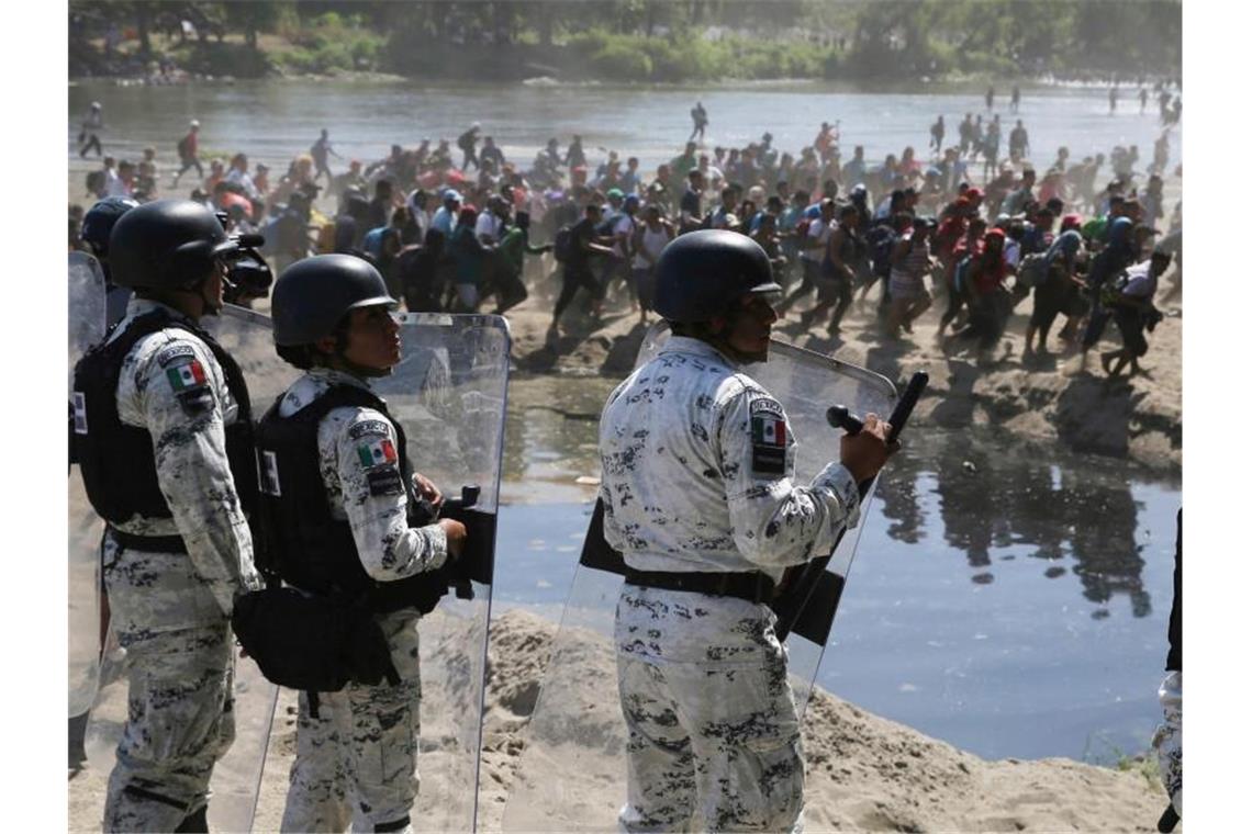Migranten passieren mexikanischen Nationalgardisten am Grenzfluss Río Suchiate zwischen zwischen Guatemala und Mexiko. Foto: Marco Ugarte/AP/dpa
