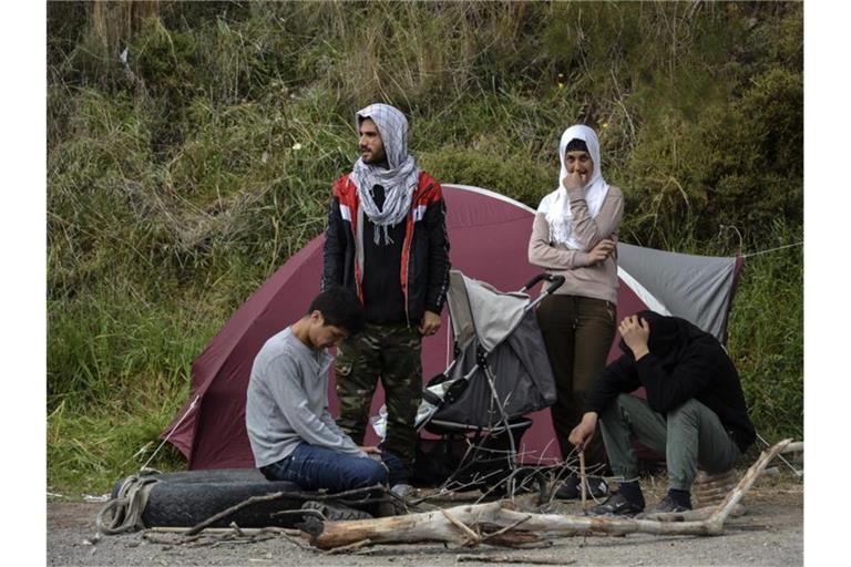 Migranten ruhen vor einem Zelt im Dorf Petra auf der nordöstlichen Ägäisinsel Lesbos in Griechenland. Foto: Panagiotis Balaskas/AP/dpa
