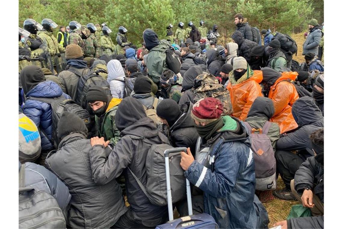 Migranten sitzen zusammen vor der Grenze in Belarus am gesperrten Übergang zu Polen. Foto: Ulf Mauder/dpa