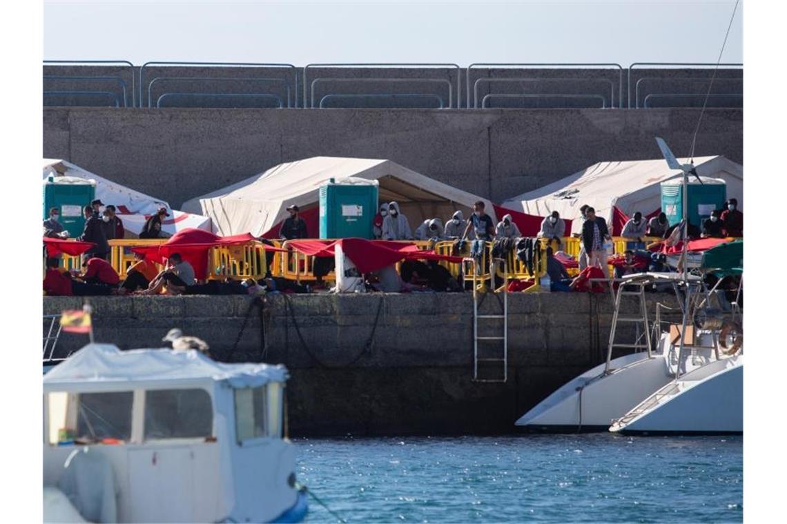 Migranten stehen an der Mole der Hafenstadt Arguineguín im Südwesten von Gran Canaria. Immer mehr Migranten wagen die Überfahrt aus Afrika auf die Kanaren. Foto: Manuel Navarro/dpa