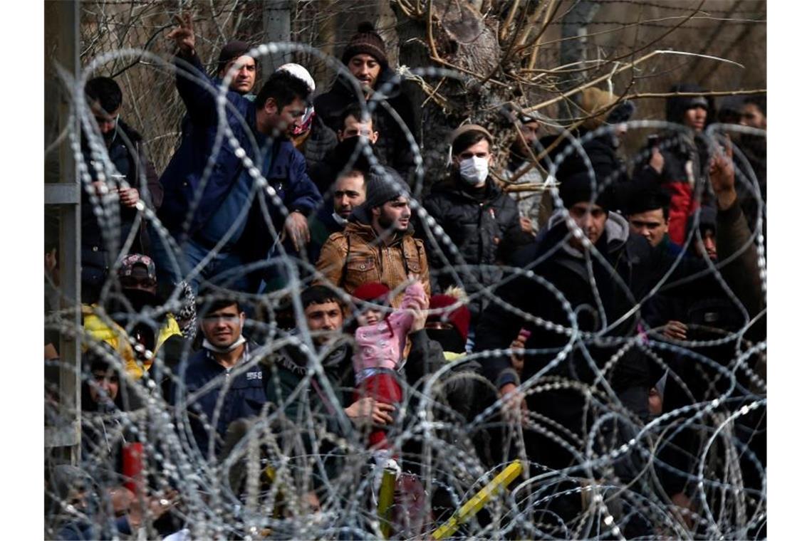 Migranten stehen hinter einem Stacheldrahtzaun nahe des griechisch-türkischen Grenzübergangs von Kastanies. Foto: Giannis Papanikos/AP/dpa