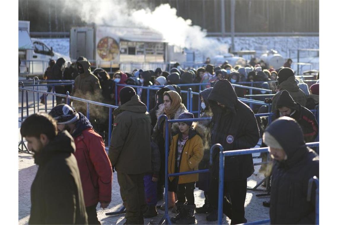 Migranten stehen in der Nähe eines Logistikzentrums an der polnisch-belarussischen Grenze an einer Essensausgabe an. Foto: Pavel Golovkin/AP/dpa