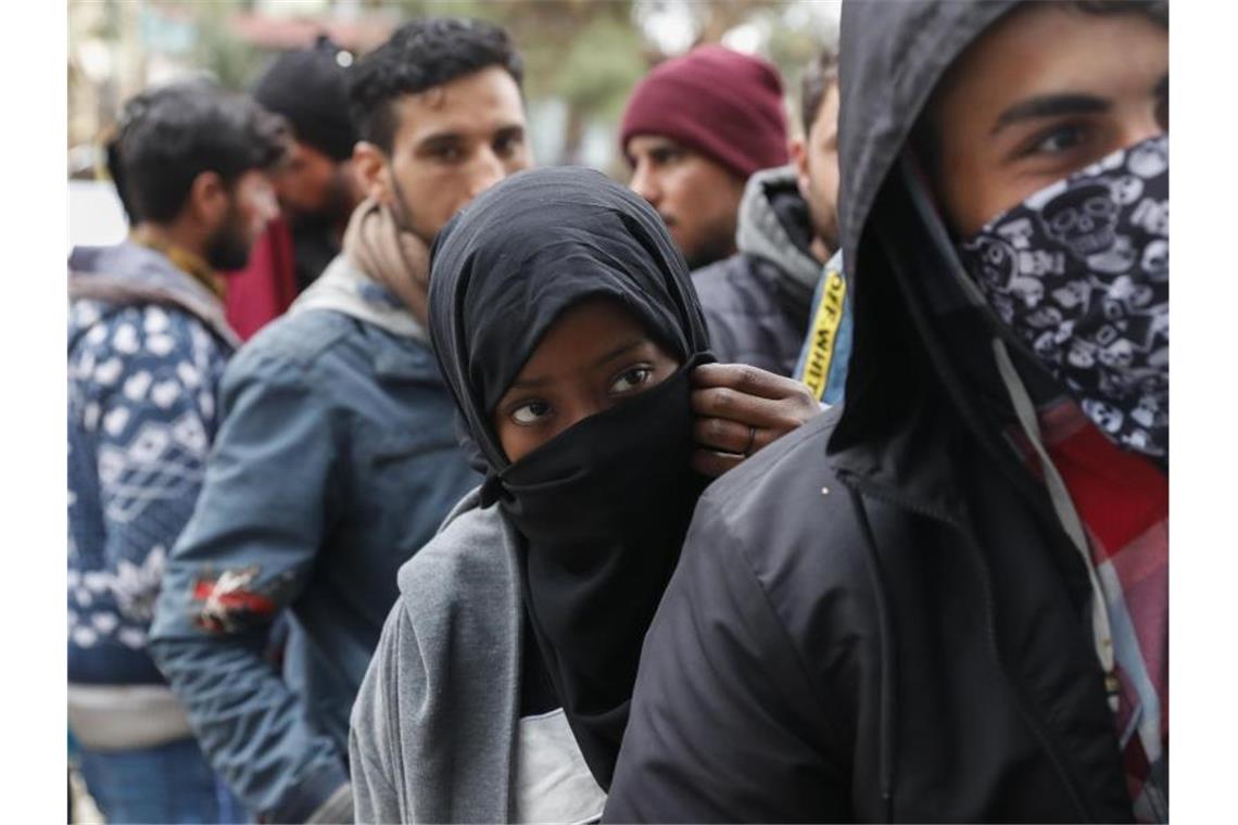 Migranten stehen in der Schlange vor einem Supermarkt in der Nähe der griechisch-türkischen Grenze. Foto: Darko Bandic/AP/dpa