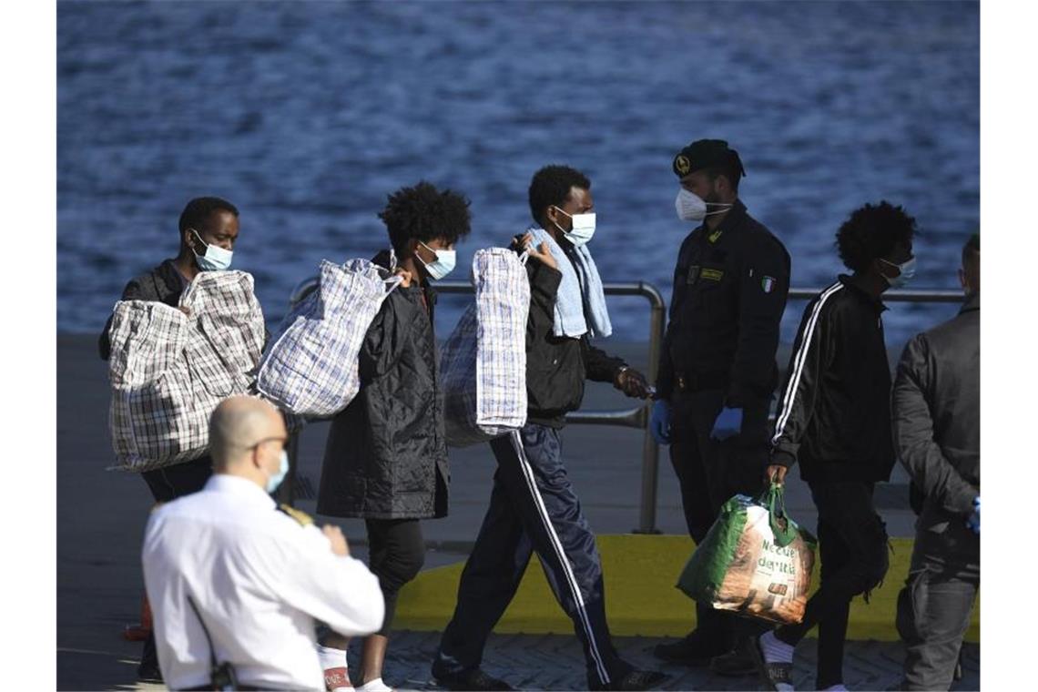 Migranten tragen ihre Habseligkeiten von Bord des Schiffes GNV Azzurra auf der sizilianischen Insel Lampedusa. Foto: Salvatore Cavalli/AP/dpa/Archivbild