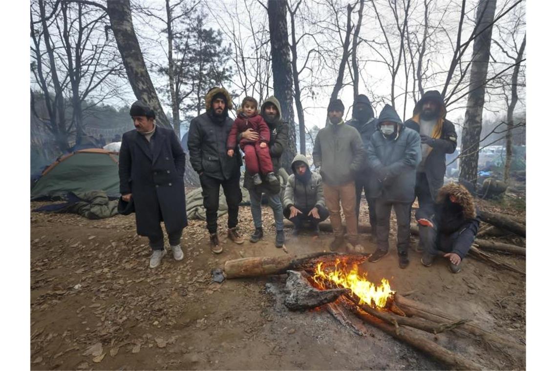 Migranten versammeln sich an der belarussisch-polnischen Grenze an einem Feuer, um sich zu wärmen. Foto: Ramil Nasibulin/BelTA/AP/dpa