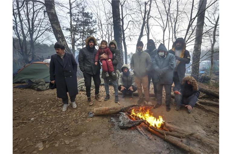 Migranten versammeln sich an der belarussisch-polnischen Grenze an einem Feuer, um sich zu wärmen. Foto: Ramil Nasibulin/BelTA/AP/dpa