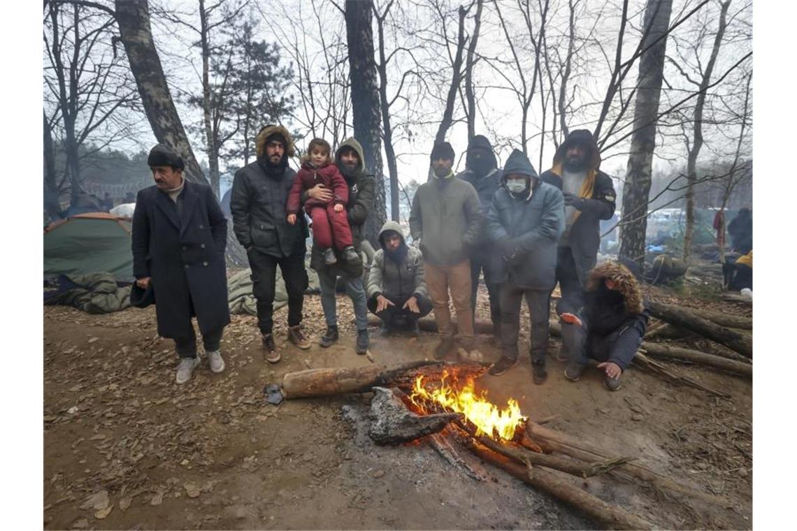 Migration über Belarus: EU mit neuem Sanktionsinstrument Migranten versammeln sich an der belarussisch-polnischen Grenze an einem Feuer, um sich zu wärmen. (Archivbild). Foto: Ramil Nasibulin/BelTA/AP/dpa
