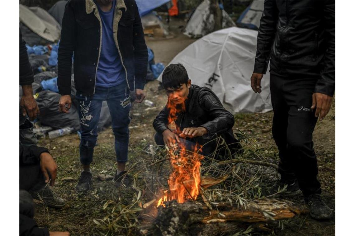 Flüchtlinge im Mittelmeer: Griechenland wieder im Fokus Migranten versuchen sich an einem kleinen Feuer neben dem Lager Moria auf der Insel Lesbos aufzuwärmen. Foto: Angelos Tzortzinis/dpa