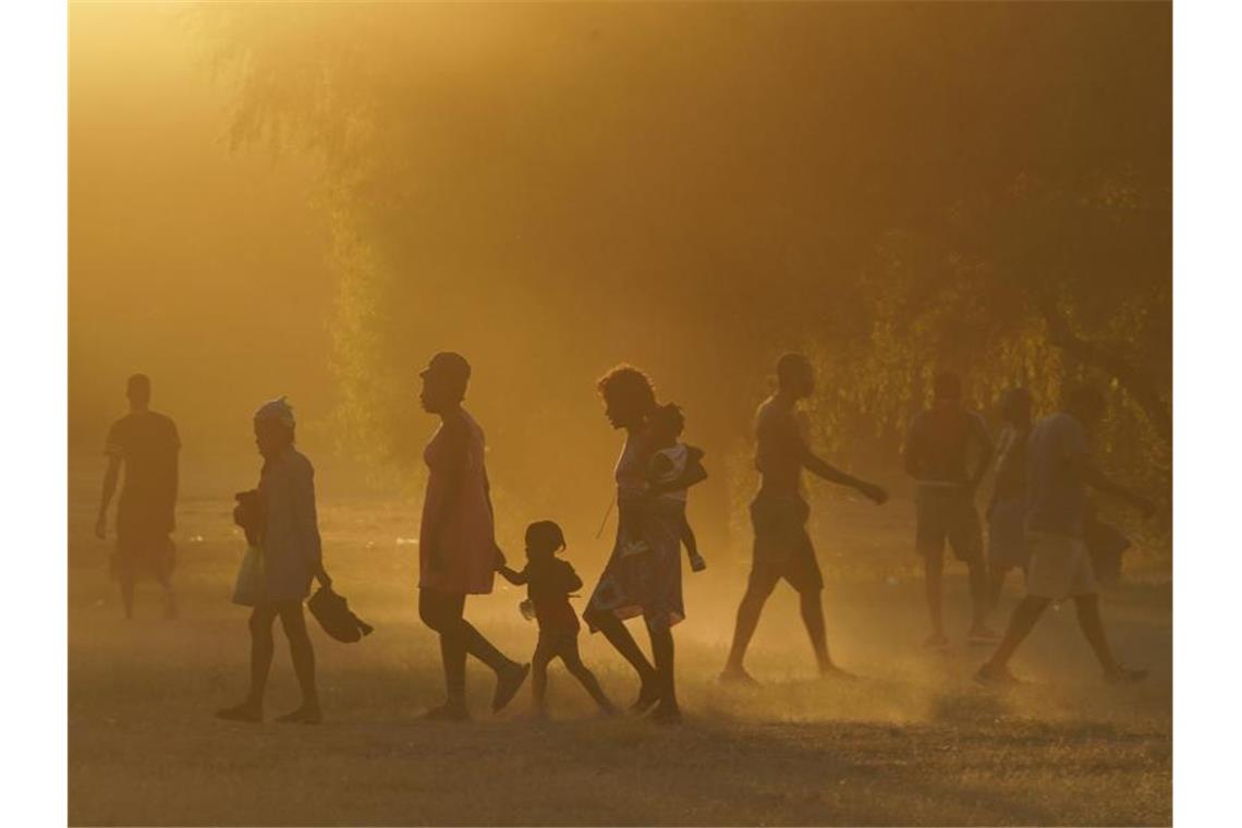 Migranten, viele von ihnen aus Haiti, gehen zu einem improvisierten Flüchtlingslager in Ciudad Acuña. Foto: Fernando Llano/AP/dpa