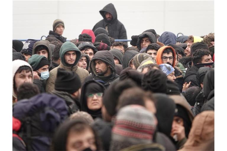 Migranten warten vor einer Lagerhalle in der Nähe der Grenze. Foto: Ulf Mauder/dpa