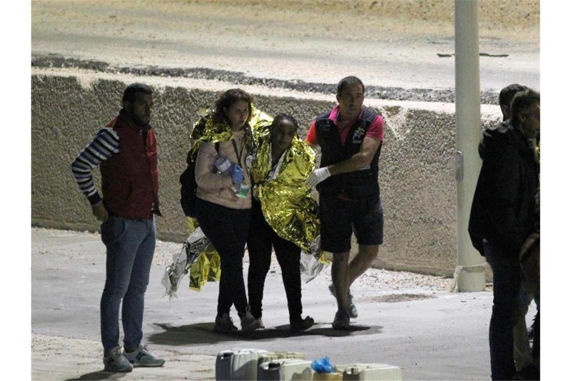 Seehofers Übergangslösung für Seenotrettung kommt kaum voran Migranten werden am Hafen von Lampedusa von Helfern begleitet. Mindestens 13 Menschen waren bei einem Bootsunglück vor der italienischen Insel ums Leben gekommen. Foto: Pasquale Claudio Montana Lampo/ANSA/dpa