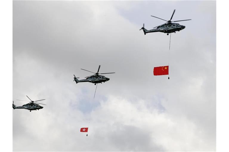 Militärhubschrauber mit einer chinesischen Nationalfahne und der Fahne der Sonderverwaltungszone Hongkong überfliegen den Goldenen Bauhinia-Plat. Es war das erste Mal seit 17 Jahren, dass keine Demonstrationen zum Jahrestag des Souveränitätswechsels am 1. Juli erlaubt waren. Foto: Kin Cheung/AP/dpa