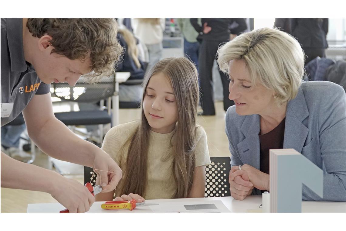 Ministerin Nicole Hoffmeister-Kraut mit der Sechstklässlerin Maria und dem Lapp-Azubi Sven Litterst beim Kupferdrahtbiegen.