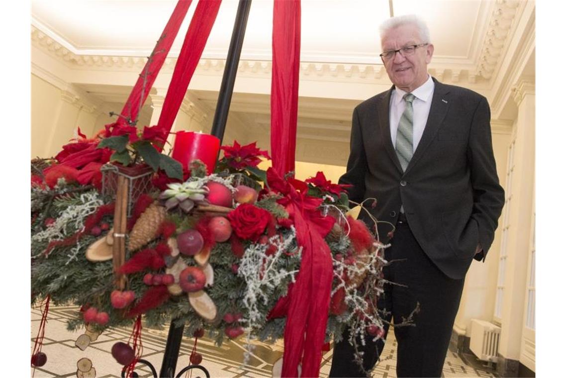 Ministerpräsident Winfried Kretschmann (Grüne) steht im Staatsministerium an einem Adventskranz. Foto: picture alliance / Franziska Kraufmann/dpa/Archivbild