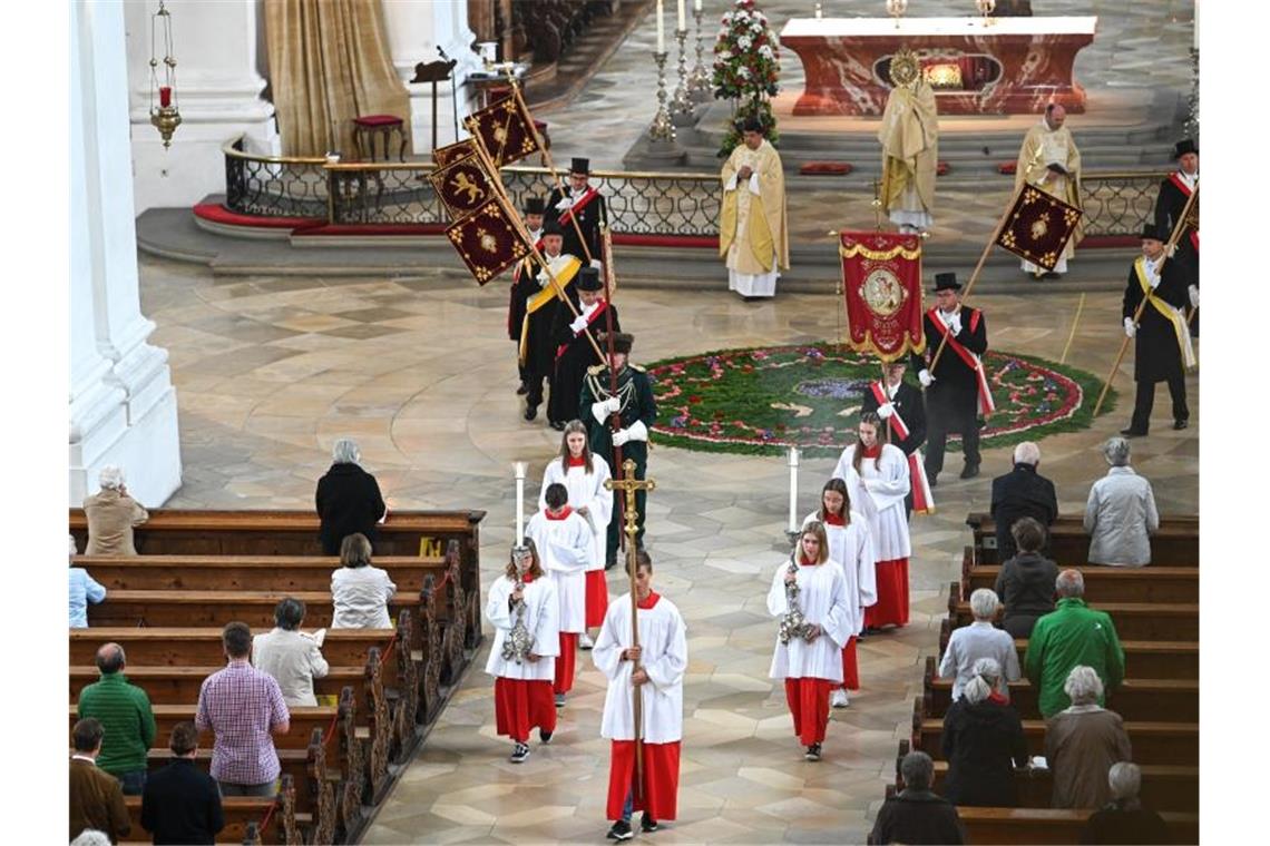 Ministranten, Pfarrer und Standartenträger laufen durch das Kirchenschiff der barocken Basilika. Foto: Felix Kästle/dpa