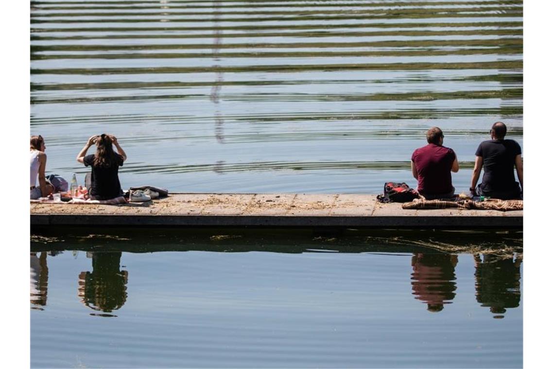 Mit Abstand zueinander genießen zwei Frauen und zwei Männer am Vatertag das sonnige Wetter am Max-Eyth-See. Foto: Christoph Schmidt/dpa/Archivbild