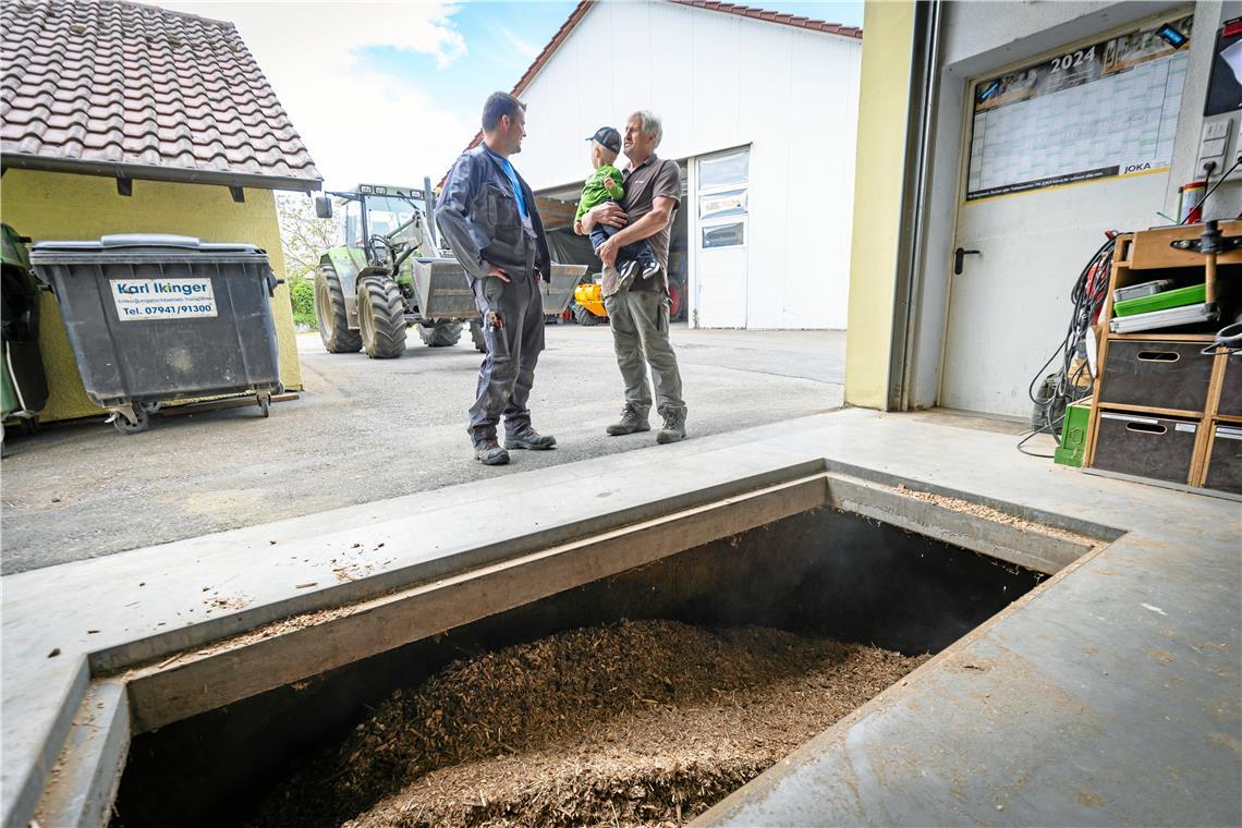 Holz: eine unbequeme Art des Heizens Mit dem Frontlader fährt Tim Kugler (links) Hackschnitzel vom Lager zur Einfüllöffnung des Hackschnitzelbunkers. Rolf Kugler (rechts) ließ die Anlage vor 17 Jahren installieren. Foto: Alexander Becher