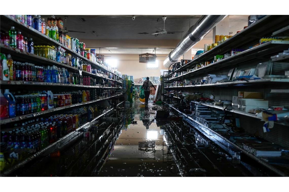 Mit der Erlaubnis des Supermarktbesitzers versorgt sich eine Person in Black River auf Jamaika nach dem Durchzug des Hurrikans "Melissa" mit Vorräten und Lebensmitteln.