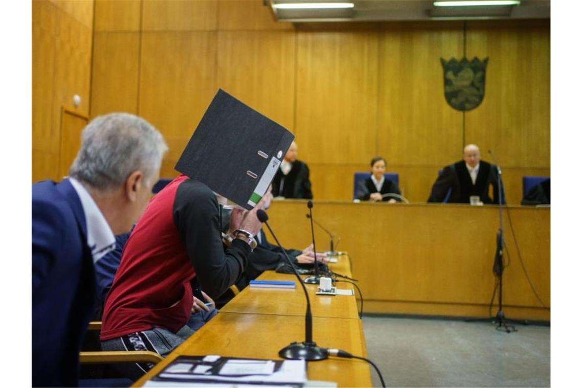 Lebenslange Haft im Prozess um Tod kleiner Jesidin Mit einem Aktenordner vor dem Gesicht nimmt der Iraker Taha Al-J. vor der Urteilsverkündung im Frankfurter Oberlandesgericht auf der Anklagebank Platz. Foto: Frank Rumpenhorst/dpa-Pool/dpa