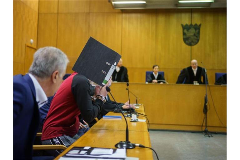 Mit einem Aktenordner vor dem Gesicht nimmt der Iraker Taha Al-J. vor der Urteilsverkündung im Frankfurter Oberlandesgericht auf der Anklagebank Platz. Foto: Frank Rumpenhorst/dpa-Pool/dpa