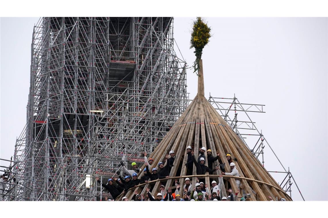 Mit einem Blumengesteck feiern die Arbeiter den Abschluss des Wiederaufbaus des Dachstuhls. Die Kathedrale Notre Dame in Paris war 2019 durch einen Brand schwer beschädigt worden.