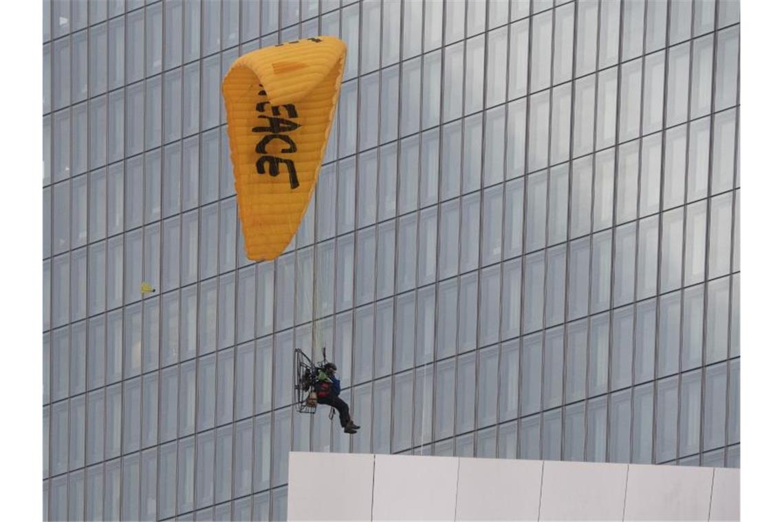 Mit einem Gleitschirm landet ein Greenpeace-Aktivist auf dem Dach der Europäischen Zentralbank (EZB). Foto: Boris Roessler/dpa