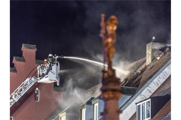 Mit einem Wenderohr löscht ein Mitglied der Feuerwehr einen Dachstuhlbrand am Münsterplatz. Foto: Patrick Seeger/dpa