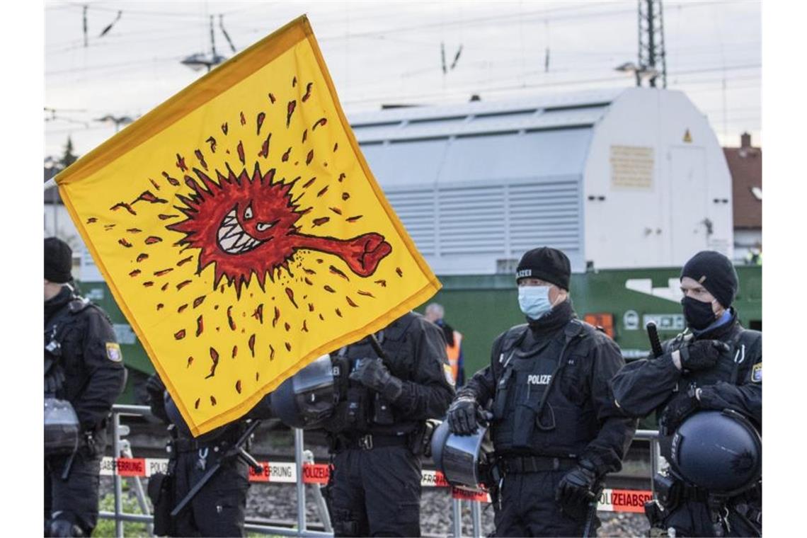 Mit einer Coronavirus-Karikatur auf einer Fahne protestieren Anti-Atomkraft-Gegner in Biblis gegen den Castor-Transport. Foto: Boris Roessler/dpa