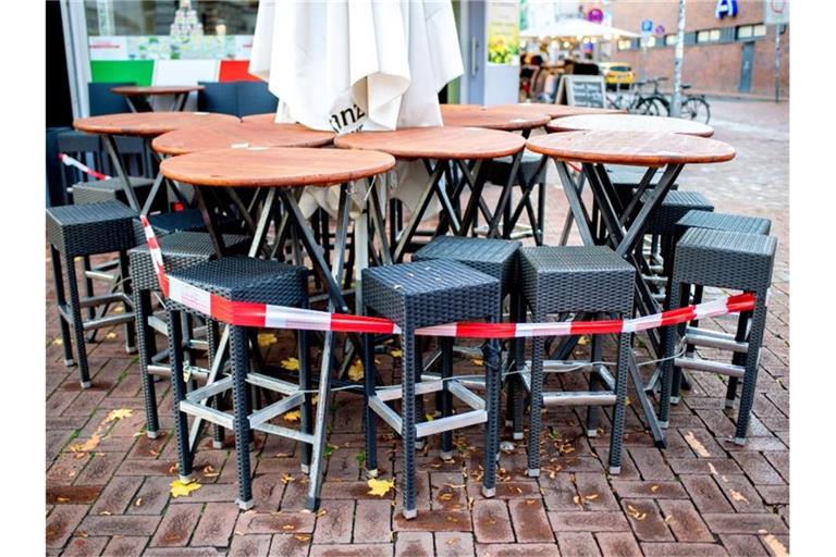 Mit Flatterband abgesperrte Tische und Stühle stehen vor einer Pizzeria in Hannover. Foto: Hauke-Christian Dittrich/dpa