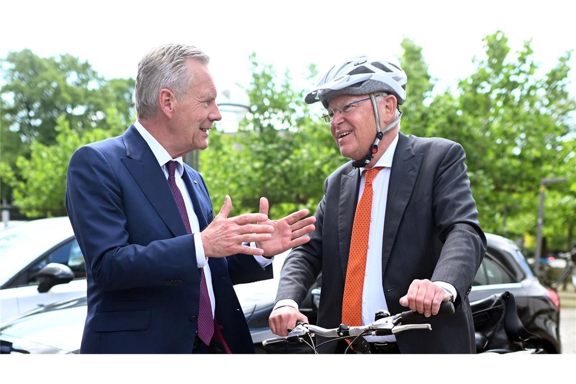 Mit Helm und Fahrrad kommt Stephan Weil (r) zur Wahl, bei der auch Christian Wulff zu Gast ist.