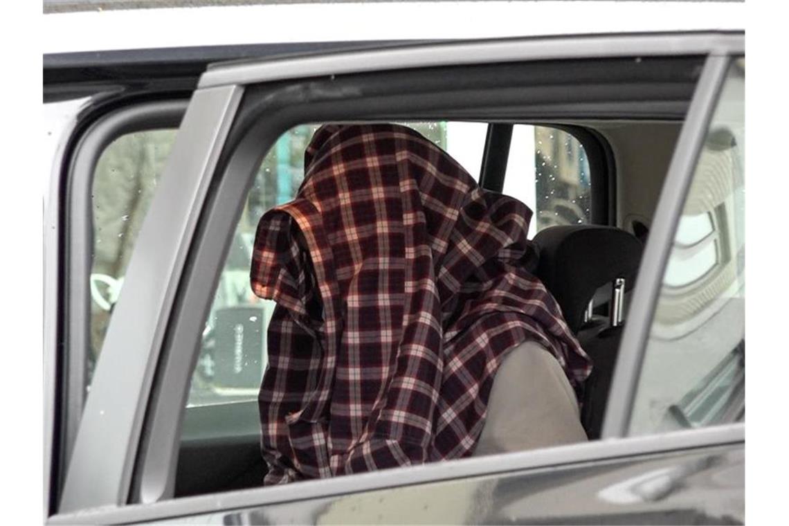 Mit Hemd über dem Kopf: Nach seiner Festnahme sitzt ein Mann in einem Auto der Einsatzkräfte. Foto: Alex Talash/dpa