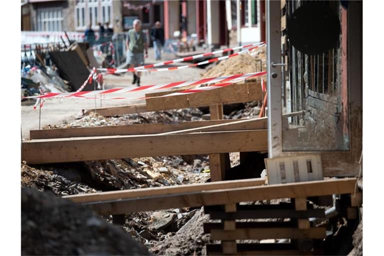 Mit Holzbrücken gelangen Anwohner in der zerstörten Altstadt von Bad Münstereifel in ihre Häuser. Die Flutkatastrophe Mitte Juli hat bislang Versicherungsschäden von rund sieben Milliarden Euro verursacht und damit mehr als bisher erwartet. Foto: Federico Gambarini/dpa
