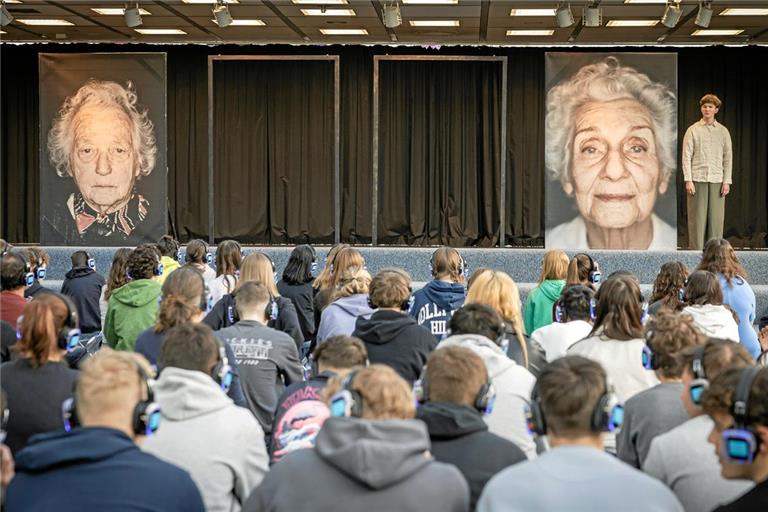 Mit Kopfhörern ausgerüstet schauen die Schülerinnen und Schüler das Theaterstück zur Ausstellung in der Sitzmulde des Bizes an. Die Stimmen des Jugendensembles der Theatergruppe Lokstoff! werden auf diese übertragen. In dieser Szene spricht Johannes Zimmermann über das Schicksal der Holocaust-Überlebenden Éva Pusztai-Fahidi (Foto rechts). Fotos: Alexander Becher