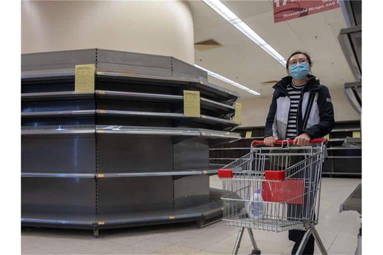 Mit Mundschutz unterwegs: Eine Frau geht in einem Supermarkt in Hongkong einkaufen. Viele Lebensmittelregale sind leer. Foto: Geovien So/SOPA Images via ZUMA Wire/dpa