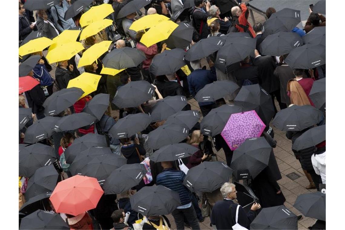 Mit Regenschirmen beteiligen sich zahlreiche Menschen auf der Buchmesse an einer Mahnwache für die Meinungsfreiheit. Foto: Boris Roessler/dpa