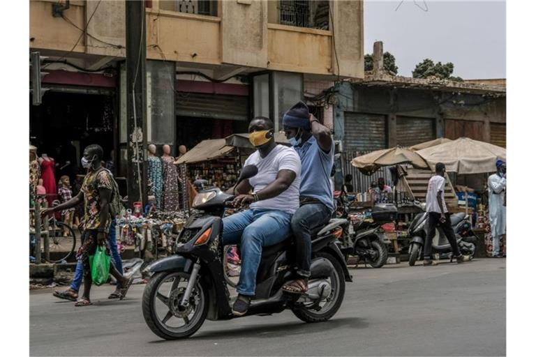 Mit Schutzmaske unterwegs auf dem Motorroller in Dakar. Von der Risikoliste gestrichen wird unter anderem Senegal. Foto: Eddy Peters/XinHua/dpa