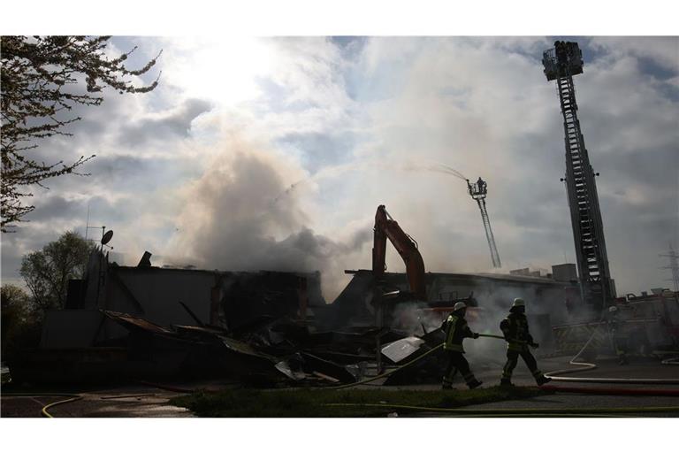 Mit schwerem Gerät arbeitet sich die Feuerwehr zu Glutnestern vor nach einem Brand in einem Club.