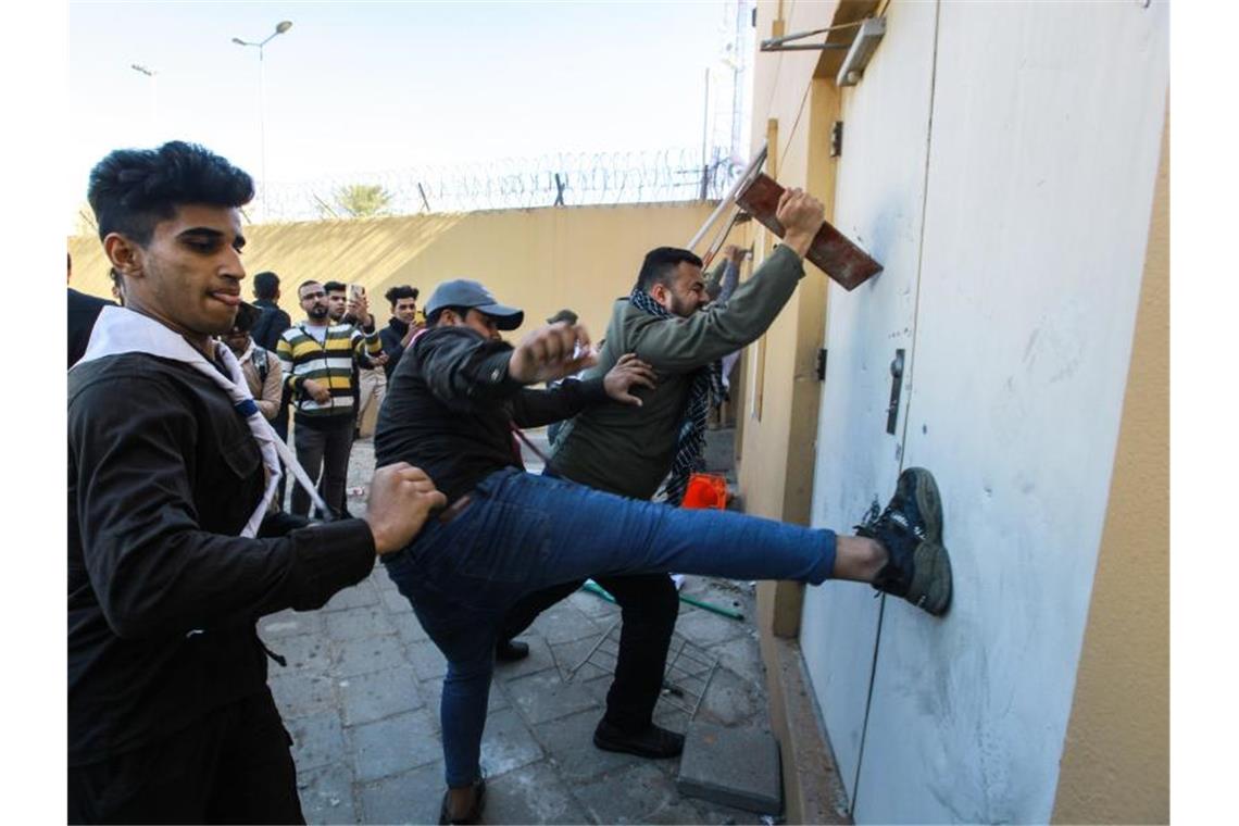 Sturm auf US-Botschaft im Irak Mit Tritten versuchen Demonstranten, die Tür der US-Botschaft aufzutreten. Foto: Ameer Al Mohmmedaw/dpa