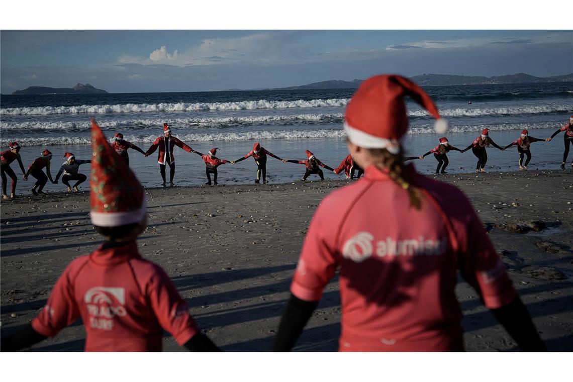 Mit Weihnachtsmannmützen verkleidete Menschen surfen während der "Papanoelada Surfera" (Surfer-Nikolaus-Aktion) am Strand von Patos.
