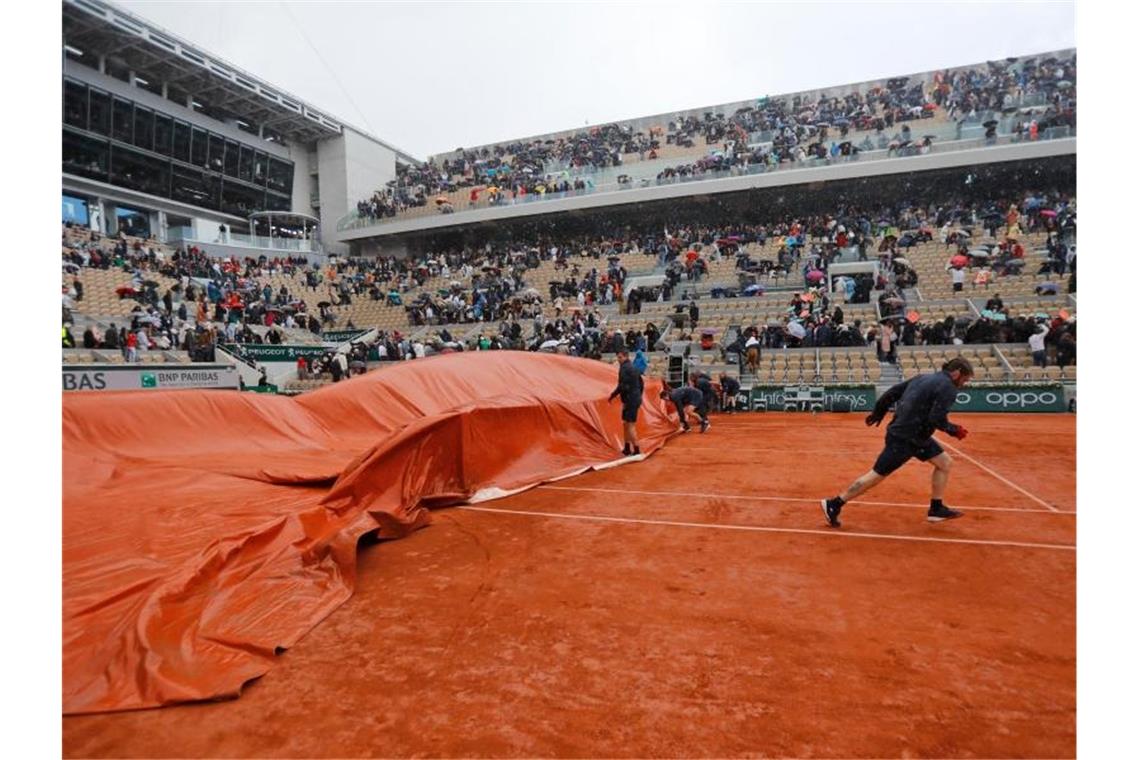 Deutsches Doppel und Barty holen Titel, Thiem fordert Nadal Mitarbeiter decken den Center Court ab, nachdem das Halbfinale wegen Regens unterbrochen wurde. Foto: Michel Euler/AP